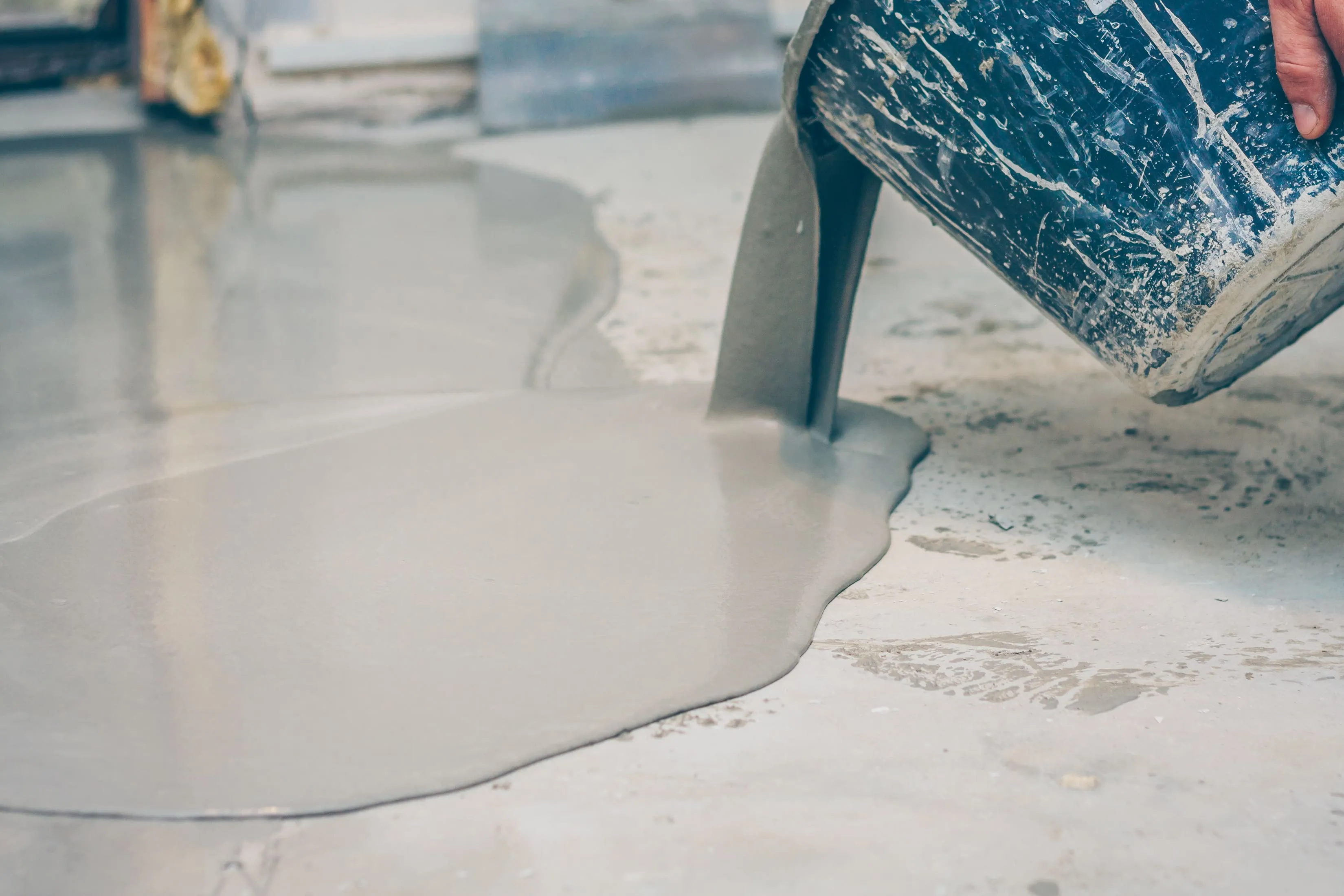 Self-leveling industrial coating being poured onto a prepared concrete floor