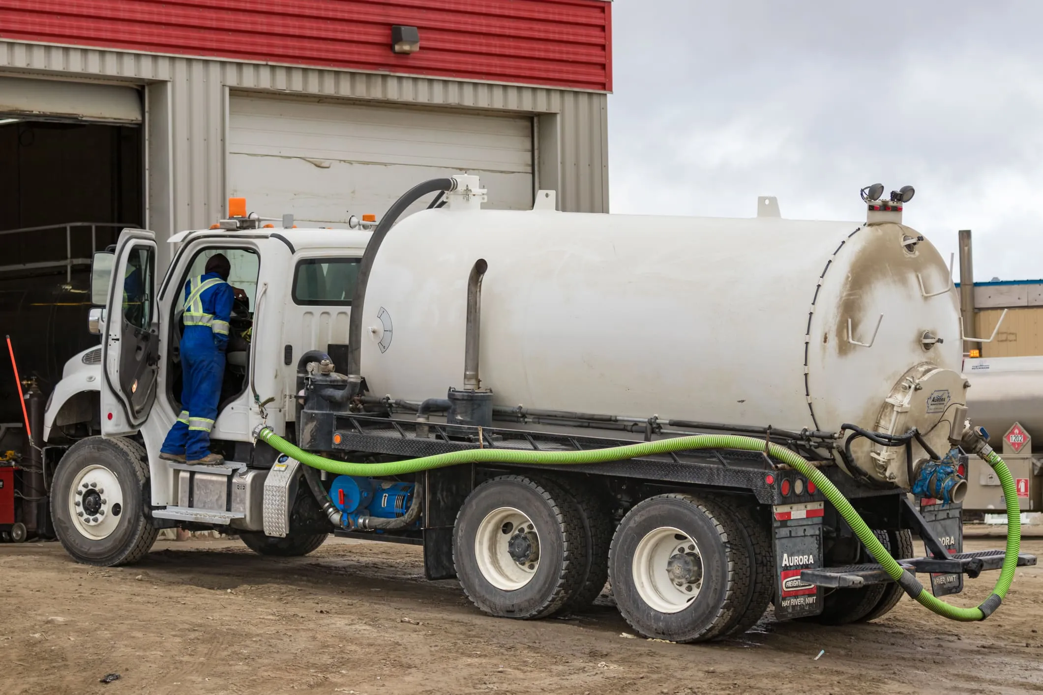 Extreme Coatings vacuum truck with a green suction hose parked at an industrial shop